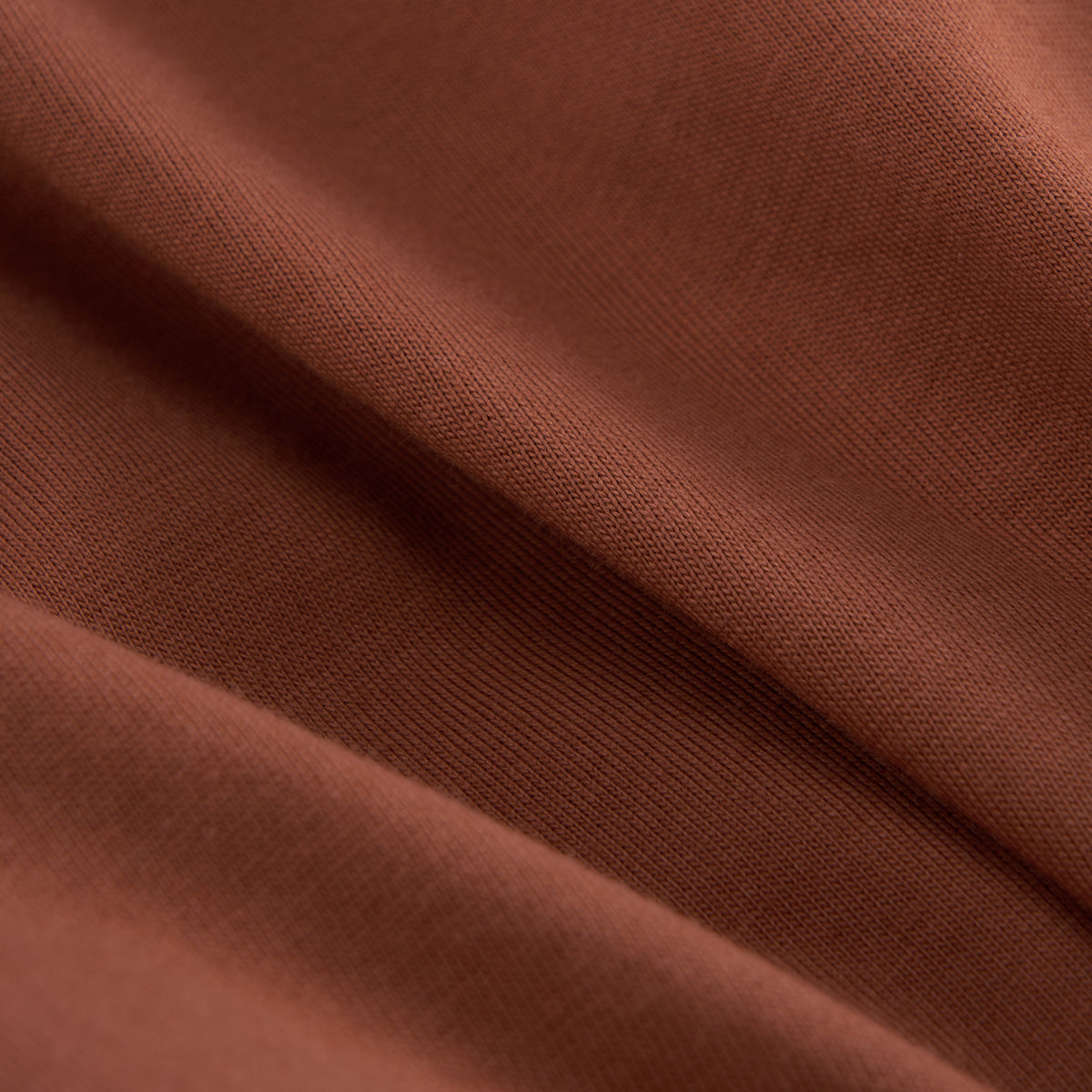 A close-up of draped brown fabric with a fine woven texture and soft folds.