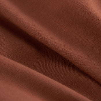 A close-up of draped brown fabric with a fine woven texture and soft folds.